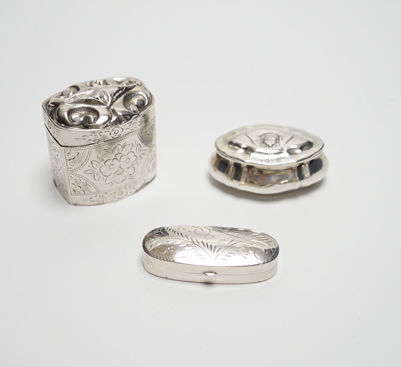 A late Victorian silver pill box with Reynold's Angel decorated cover, 47mm, a modern silver pill box and a Dutch white metal box.
